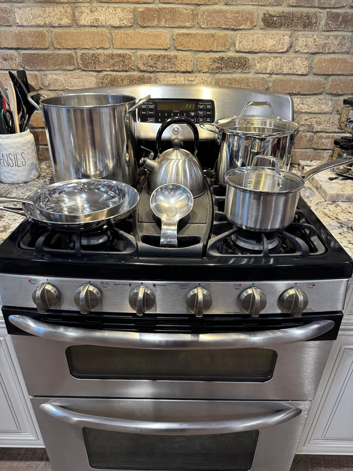A kitchen with a gas stove, oven, and various pots and pans.