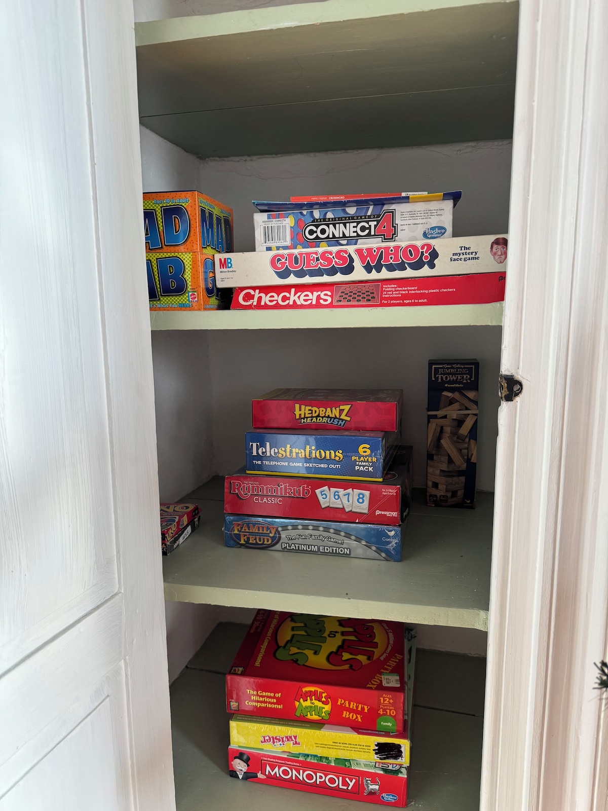 A shelf with various board games including Connect 4, Checkers, and Monopoly.