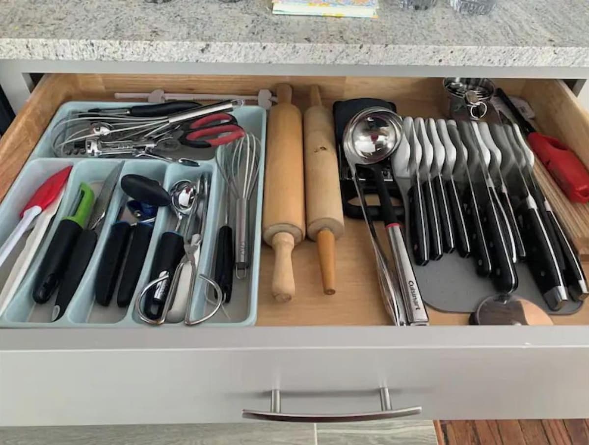 A kitchen drawer with utensils and tools organized in compartments.