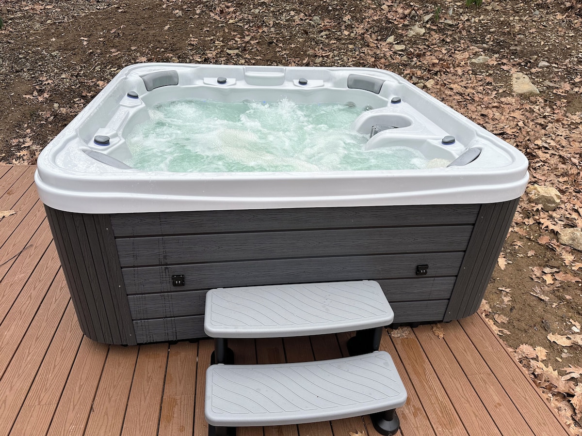A hot tub with a wooden deck and a step for access.