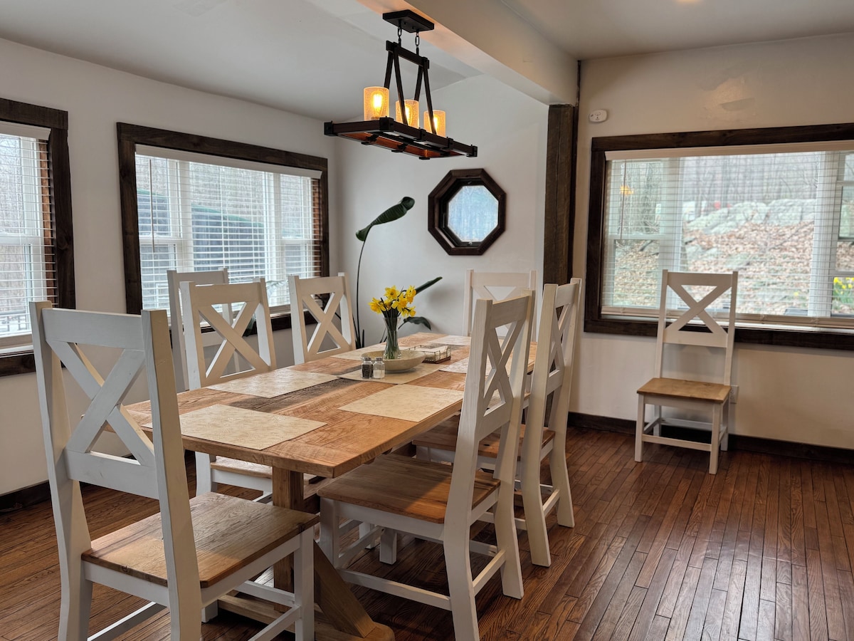 A dining area with a wooden table, white chairs, and a chandelier.