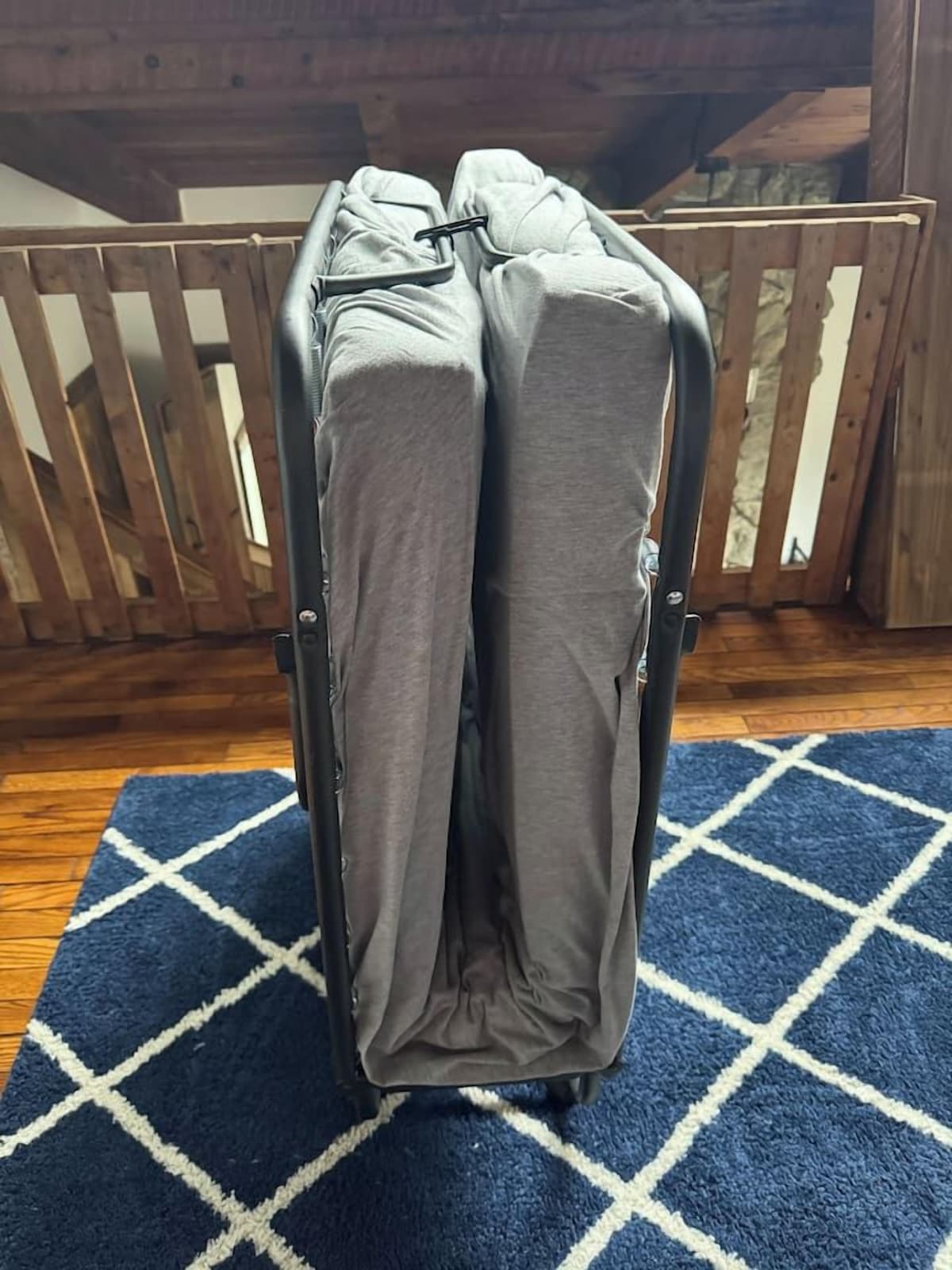 A luggage cart with grey luggage on a blue patterned rug.